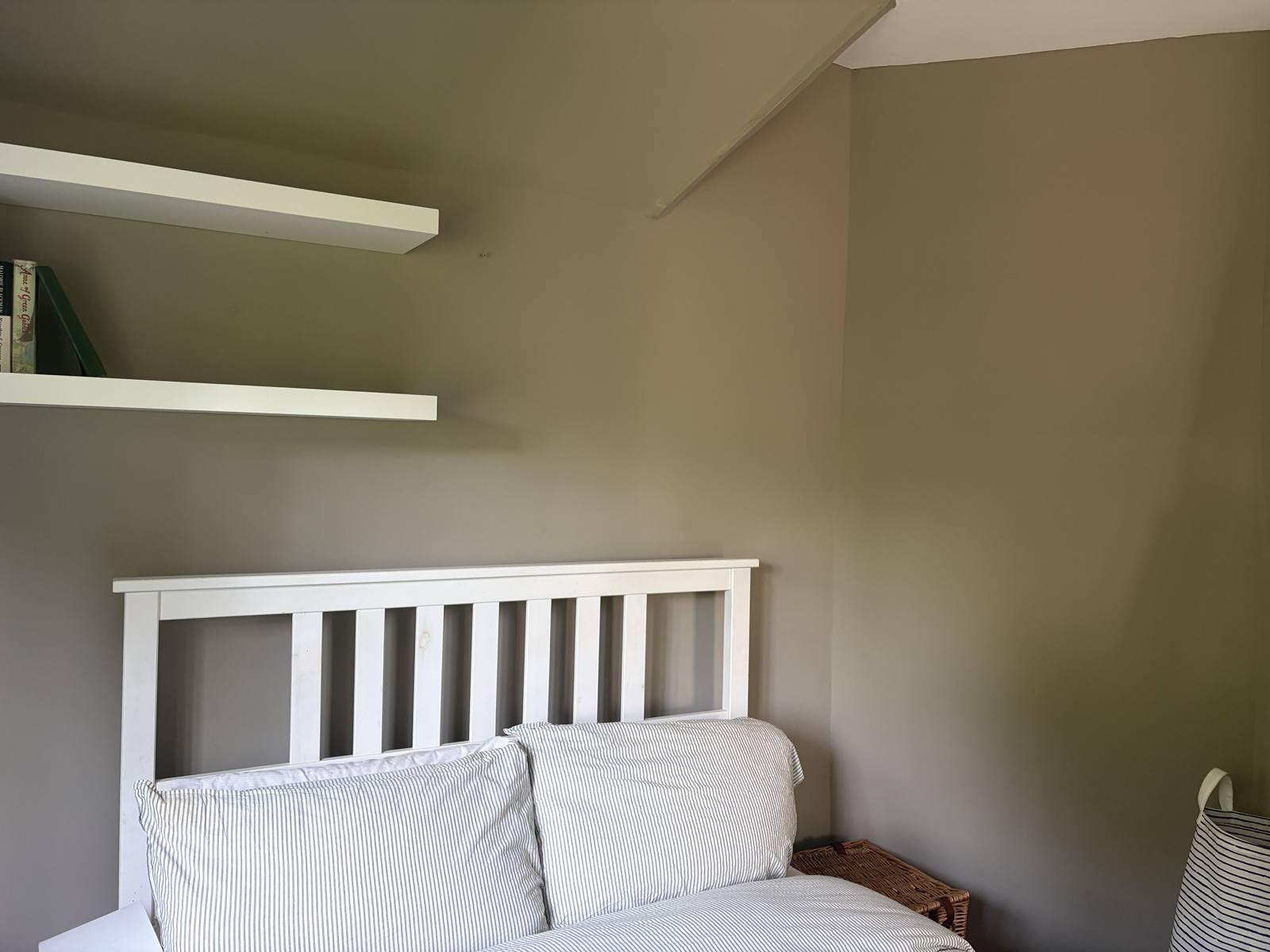 Neptune Honed Slate wall against white floating shelves and bed frame in daylight, Hertfordshire
