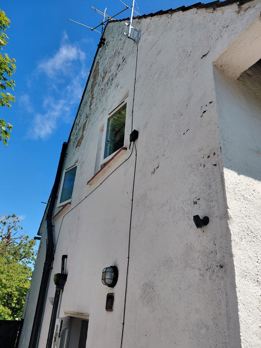 Two-storey house with failing render — algae, cracks and sections missing