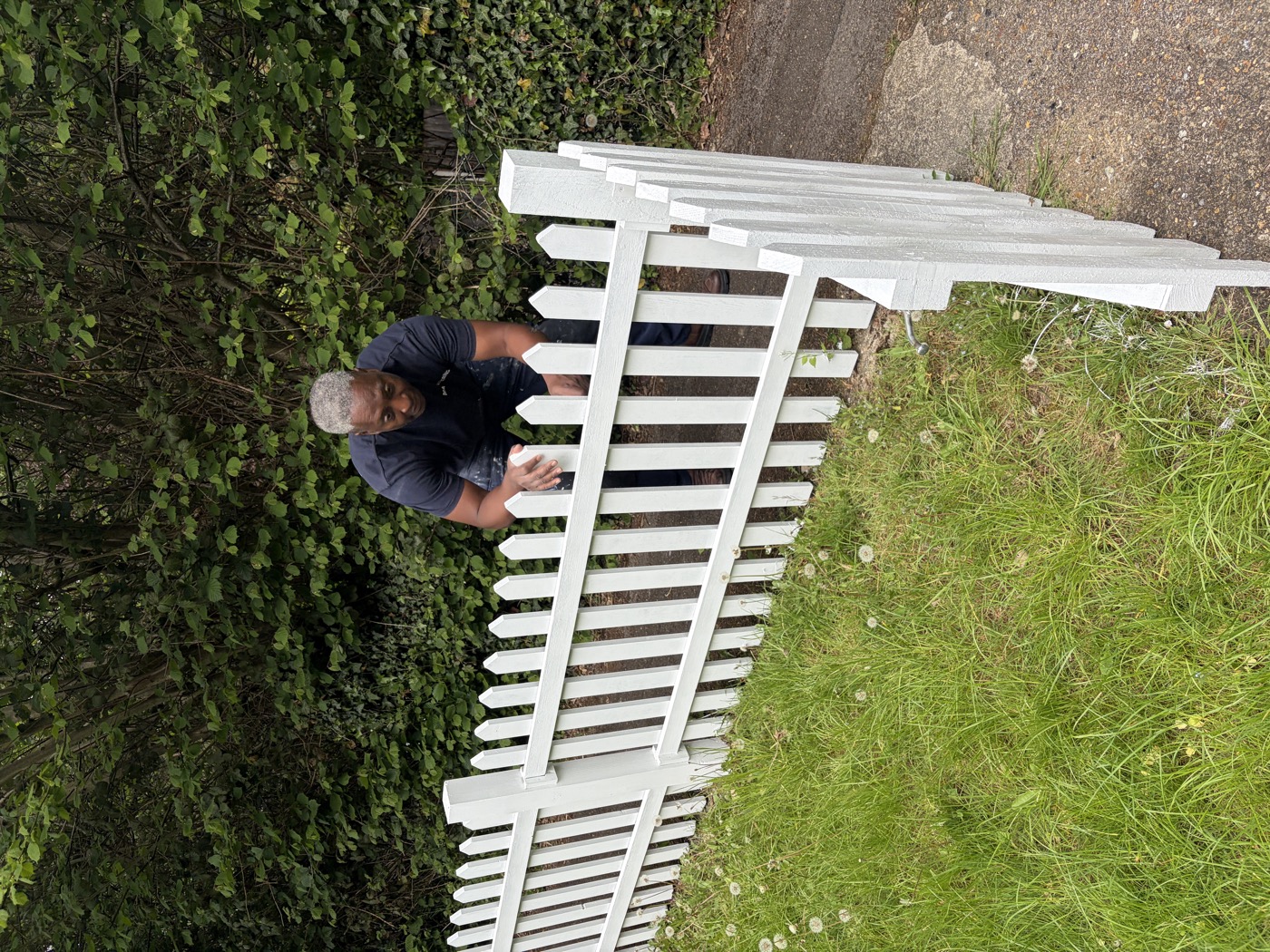 Roger Amada applying final coat to newly built white picket fence